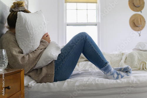 Woman Burying her Face in a Pillow on Bed photo