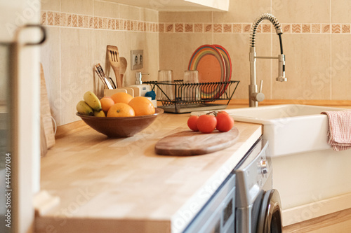 Close up of modern kitchen with sink and faucet, fruits and vegetables on the counter.