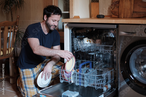 Housekeeper Removing Dishware From Open Dishwasher