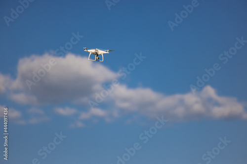Unmanned aerial vehicle against the blue sky and clouds - drone in the air
