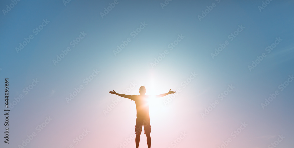Fototapeta premium People happiness, hope, light , and power concept. Man with arms raised to the colorful sky 