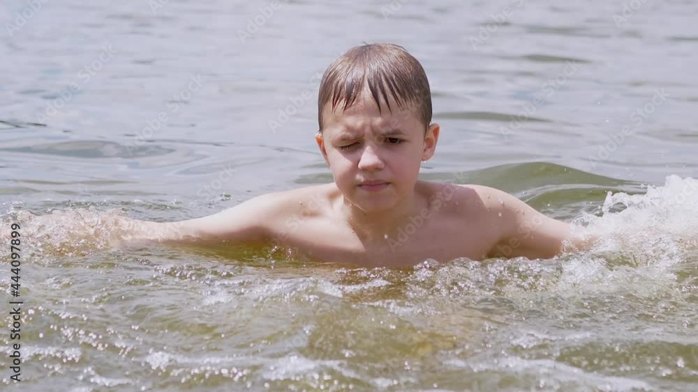 Child Splashes in the Water, the River, Creating Waves, Splashes, Whirlpools. Hand spinning in water. Boy enjoys playing with water drops, swimming. Active teenager bathes in a pond in summer. Zoom. Child Splashes in the Water, the River, Creating Waves, Splashes, Whirlpools. Hand spinning in water. Boy enjoys playing with water drops, swimming. Active teenager bathes in a pond in summer. Zoom.