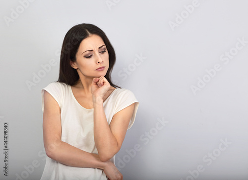 Beautiful serious angry thinking young woman looking up on empty copy space