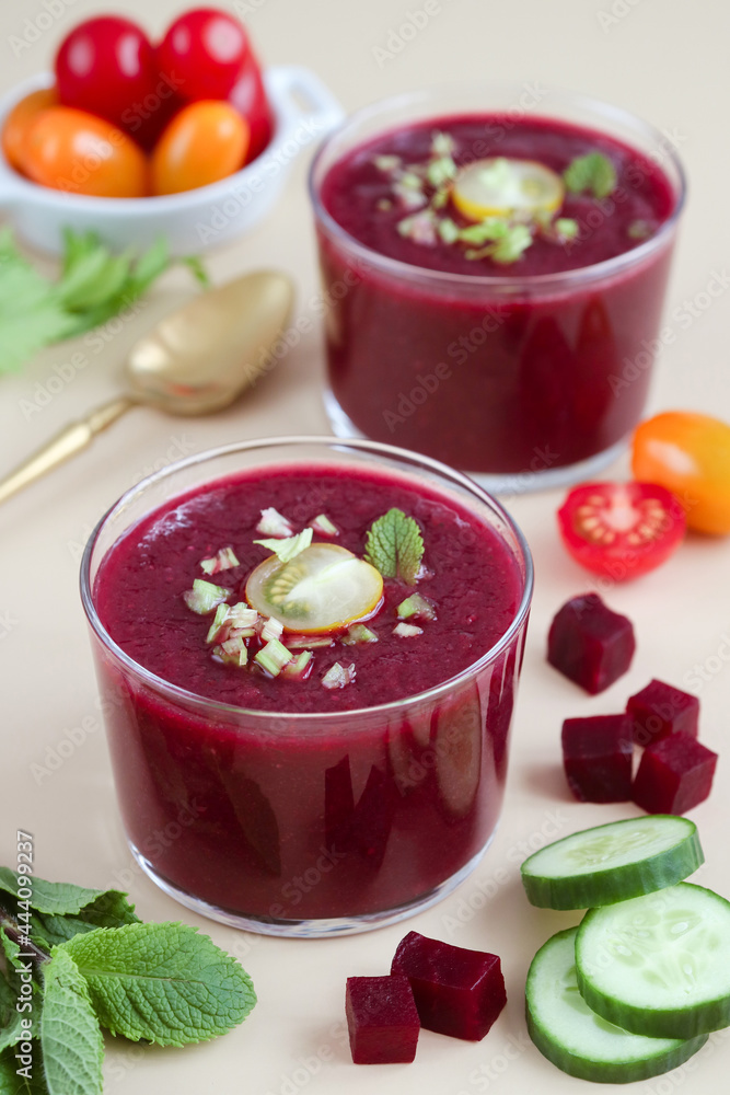 A verrine of cold beetroot gazpacho chilled soup with colorful tomatoes cherry, mints, cucumbers, spoon in background. It's a cold blended mix assortment of raw vegetables. A verrine of cold beetroot gazpacho chilled soup with colorful tomatoes cherry, mints, cucumbers, spoon in background. It's a cold blended mix assortment of raw vegetables.