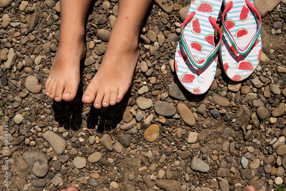 slippers flip flops and children's feet on a stone beach - obrazy, fototapety, plakaty 
