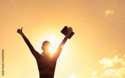 Fotografie silhouette of inspire female holding up book to the sky with thumbs up