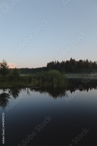 summer evening twilight view on picturesque plain lake surface with reflections of sky and trees © paralisart