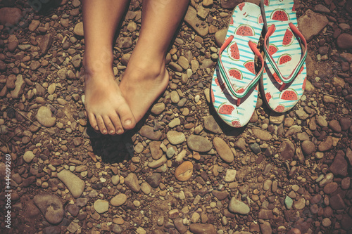 slippers flip flops and children's feet on a stone beach