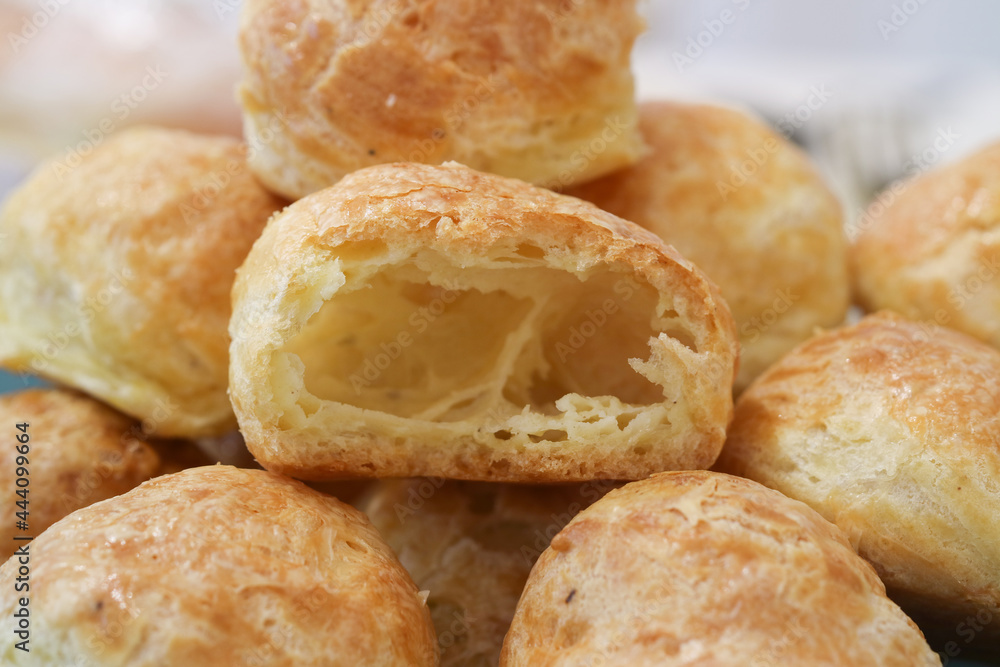 Close up of French cheese puff or Gougères in a plate with a cut piece. It's a traditional filled pastry bites, made with savory choux dough, served as appetizer. It be made with different variations 