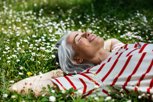 Delighted middle aged female lying on grass photo