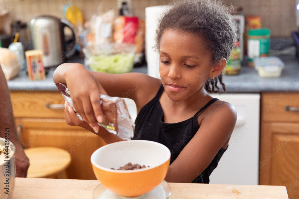 Young girl measuring chocolate chips for her baking Young girl measuring chocolate chips for her baking