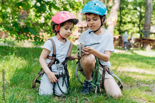 Beautiful children, a boy and a girl in protective helmets with a rope in their hands. Children spend time outdoors in the rope park