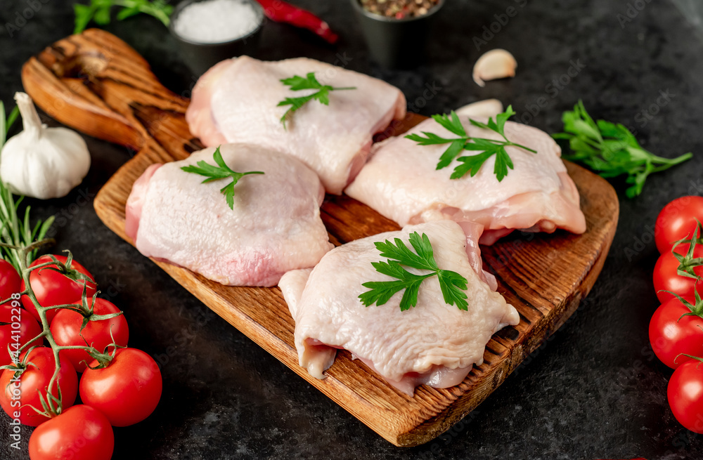 raw chicken thighs with spices and herbs on a stone background