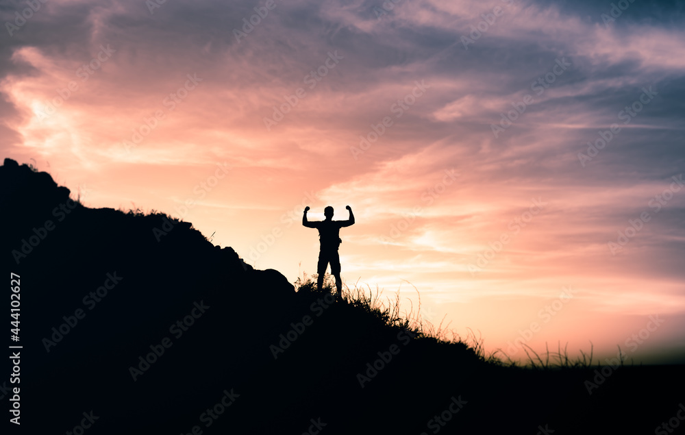 Goal setting! Strong determined man on a mountain top flexing his arms up to the sky. 