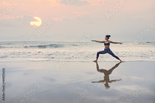 Indonesian woman doing yoga on a beach with setting sun photo