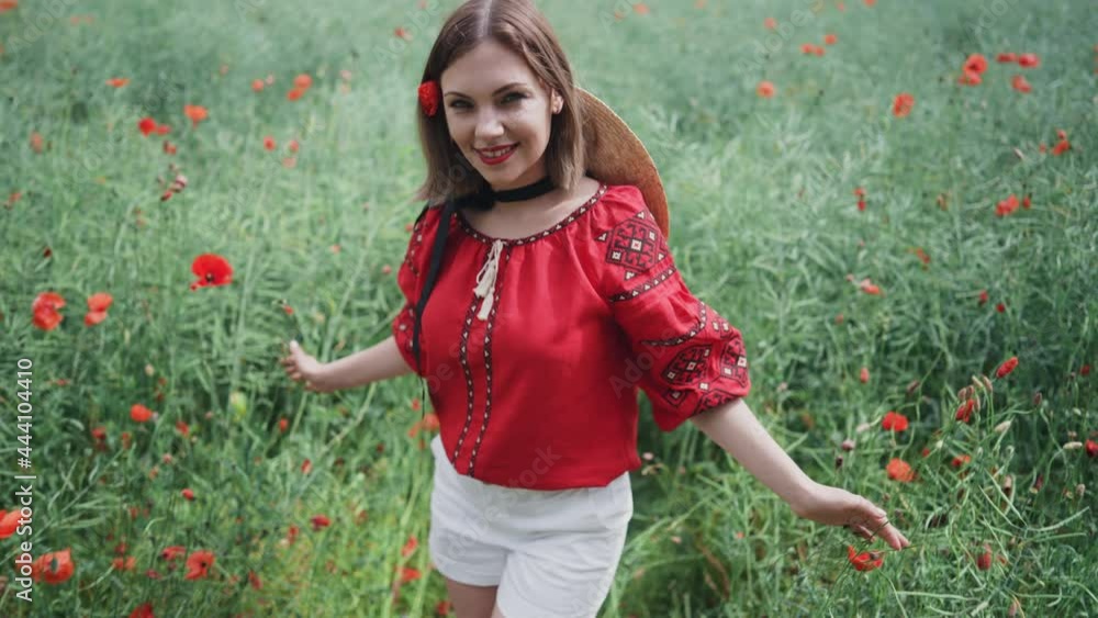 Young pretty woman smiling to camera in poppies red field. Nature, flowers background. Lady in Ukrainian embroidered shirt. National traditional clothing. Culture concept. Young pretty woman smiling to camera in poppies red field. Nature, flowers background. Lady in Ukrainian embroidered shirt. National traditional clothing. Culture concept.