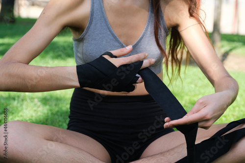 Unrecognizable no binary person wearing muay thai hand wraps sitting on grass