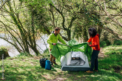 Traveling couple preparing tent for camping in nature photo