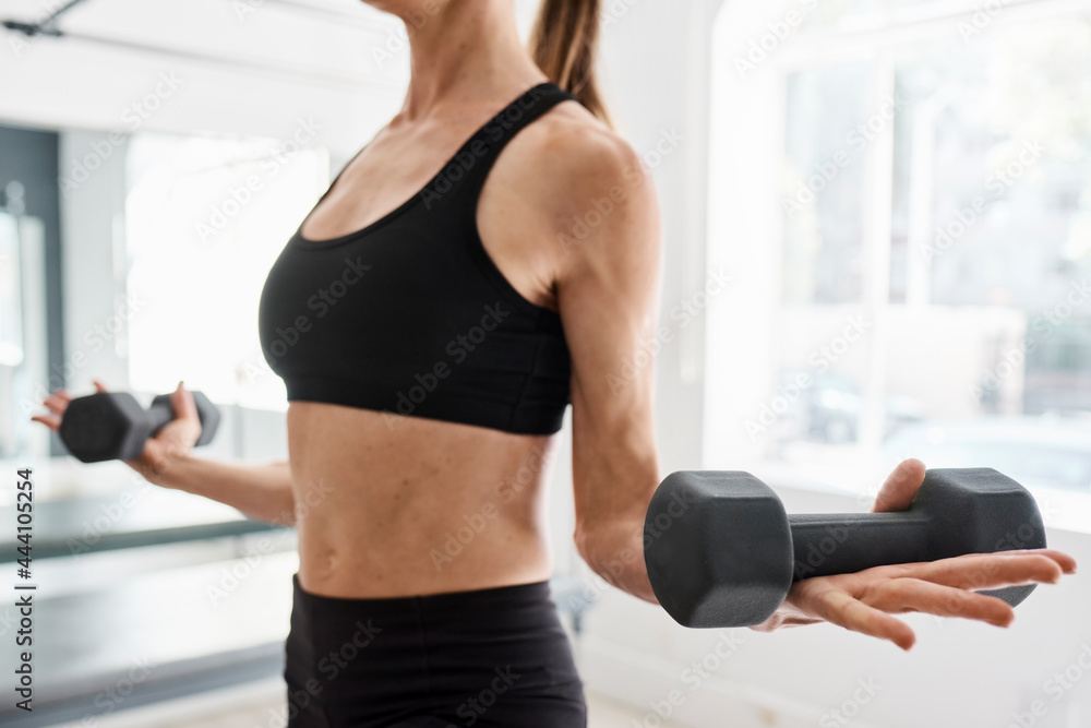 Crop sportswoman doing exercises with dumbbells in gym Crop sportswoman doing exercises with dumbbells in gym