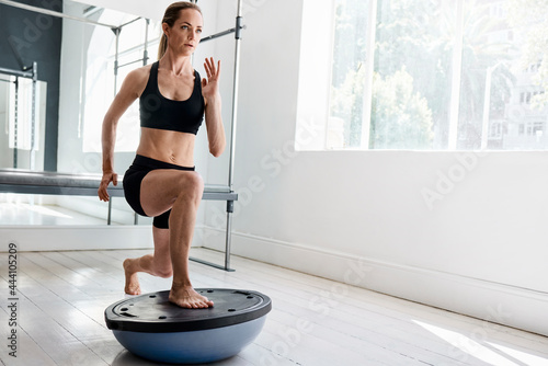 Serious sportswoman doing lunge exercise on bosu ball photo
