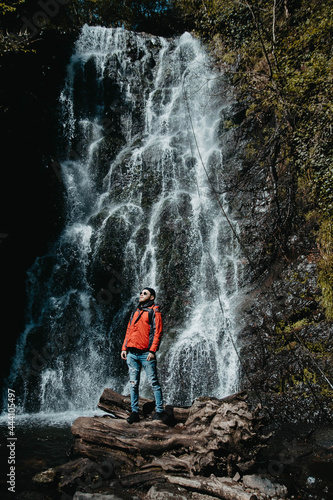 male traveler stands at a waterfall in the forest © velimir