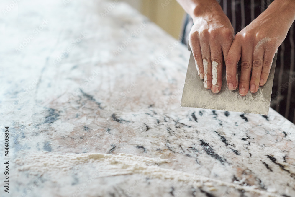 Crop baker scraping marble table Crop baker scraping marble table