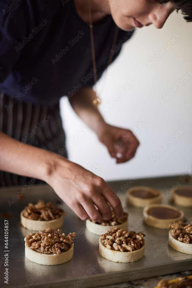 Crop woman decorating tarts with walnuts Crop woman decorating tarts with walnuts