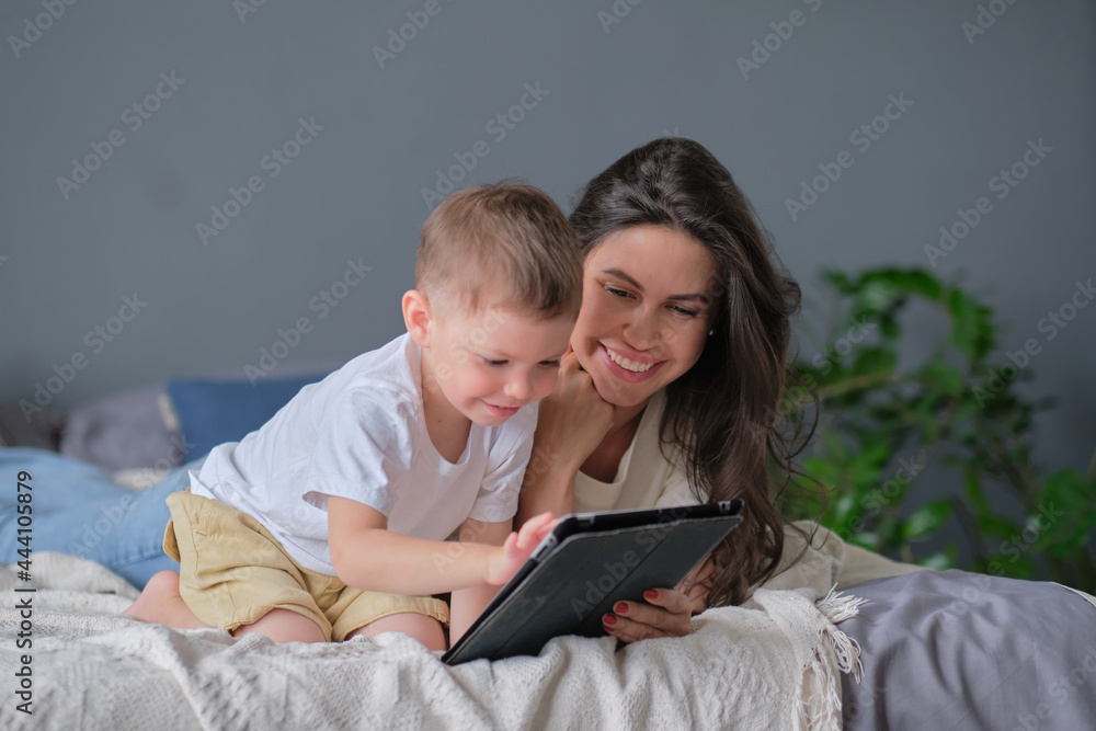mother and son with tablet at home. Mother showing media content on line to her son in a tablet in the living room in a house interior mother and son with tablet at home. Mother showing media content on line to her son in a tablet in the living room in a house interior