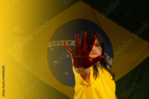 child with bloody hands and brazil flag in the background