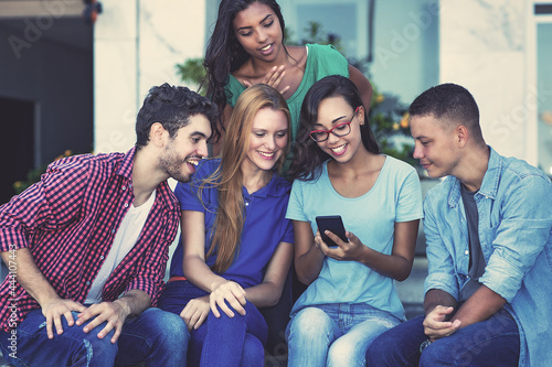 Influencer girl with mobile phone and group of young adult friends