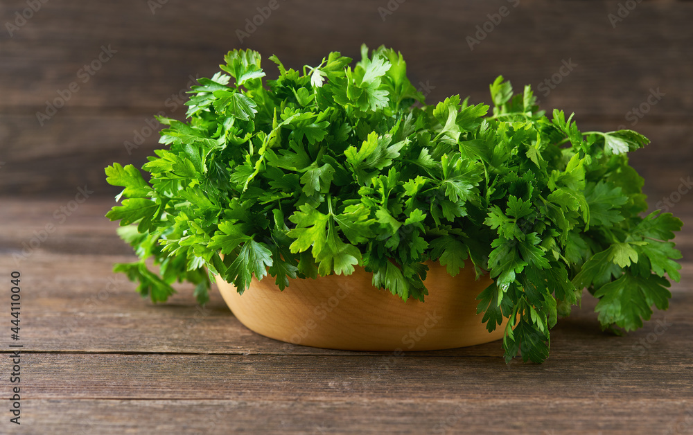 fresh parsley in a wooden bowl on the table, selective focus, rustic style. fresh parsley in a wooden bowl on the table, selective focus, rustic style.