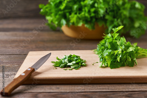 Fresh chopped green parsley leaves on a cutting board, selective focus.