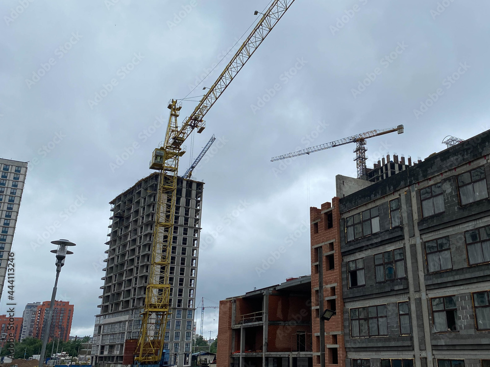 Construction of new new buildings of houses with cranes and construction equipment in the microdistrict of a big city