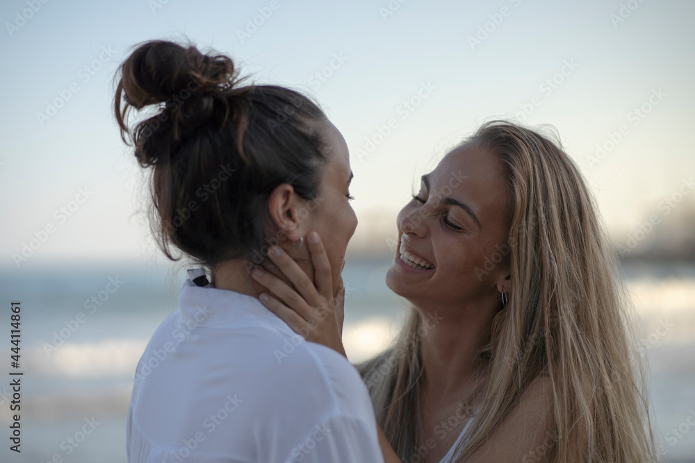 A couple of woman kissing on the beach on a summer day. A couple of woman kissing on the beach on a summer day.