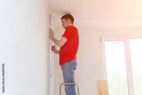 Man repair worker checking level of the wall with the bubble level tool. Renovation apartment concept