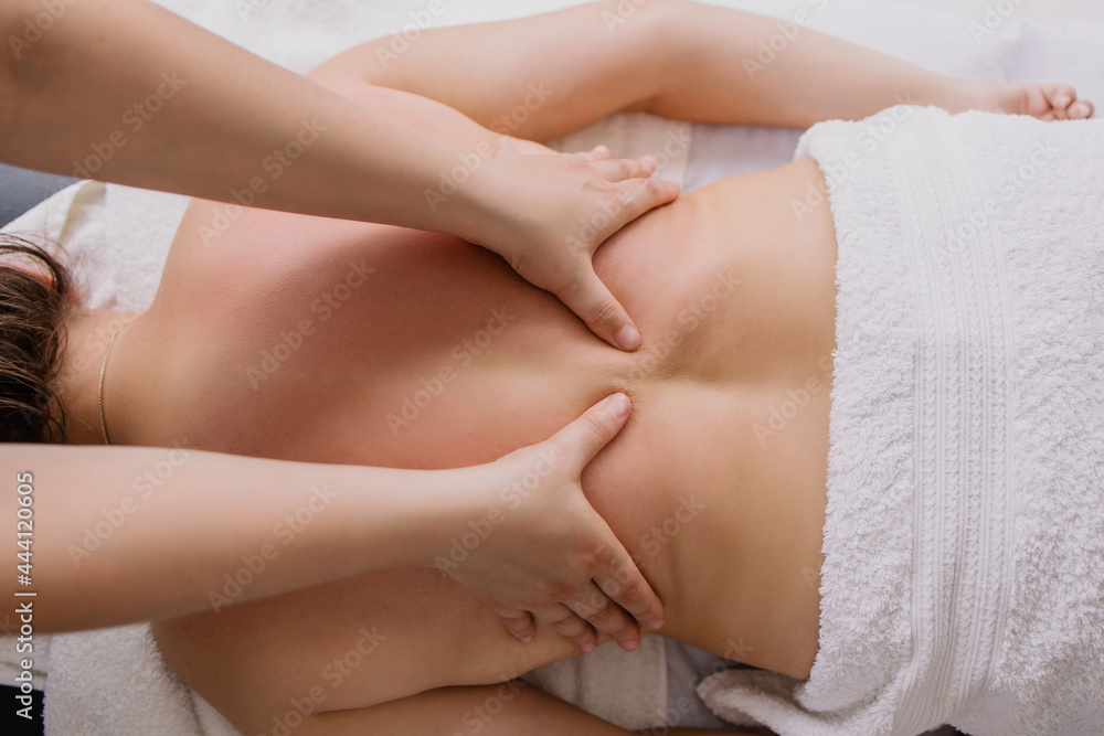 woman is lying on a back massage. Treating muscle pain. masseur kneads the client. Chiropractor at work. Osteopath massages. Relaxation therapy. Shoulders and lower back treatment. Patient in spa
