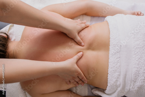 woman is lying on a back massage. Treating muscle pain. masseur kneads the client. Chiropractor at work. Osteopath massages. Relaxation therapy. Shoulders and lower back treatment. Patient in spa © Antipina