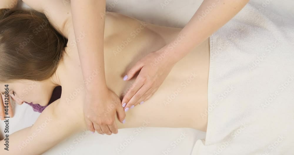 Young beautiful woman having professional massage in spa salon. Masseur kneads muscles of back. Top view Young beautiful woman having professional massage in spa salon. Masseur kneads muscles of back. Top view