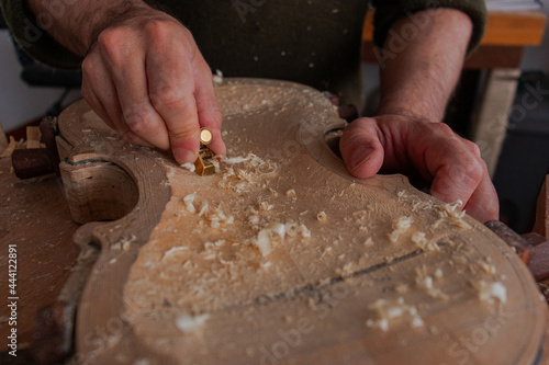 Luthier is using a little tool to give shape the violin body  