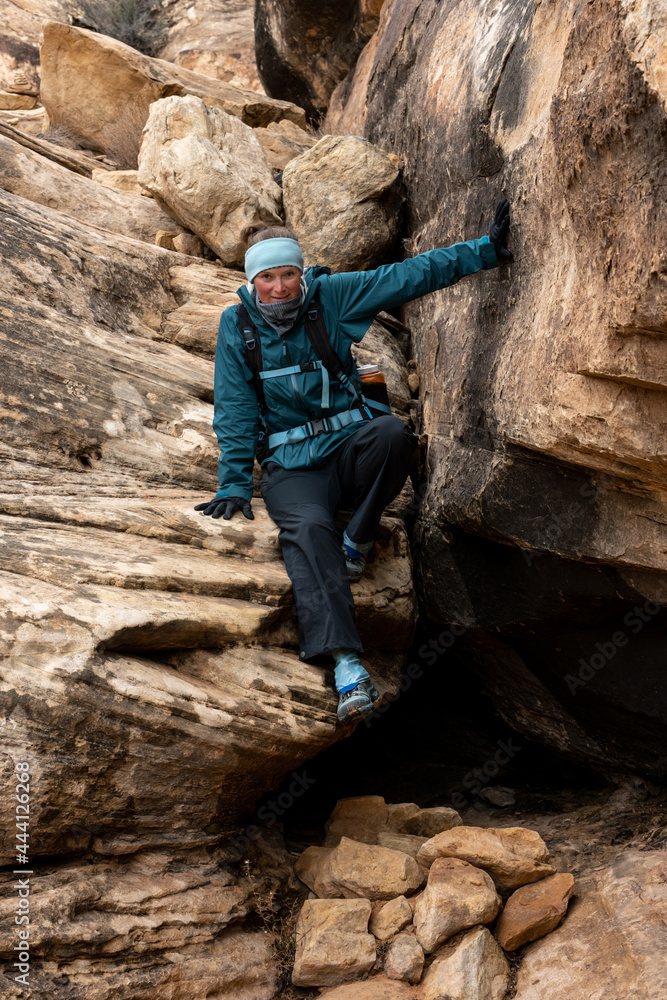 Woman in Rain Gear Prepares to Jump Off a Large Boulder Woman in Rain Gear Prepares to Jump Off a Large Boulder