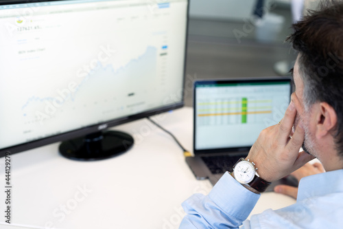 Stock broker businessman analyzing graphs and charts and talking by phone