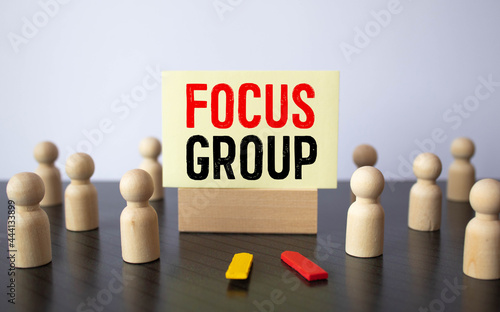 Focus group word handwritten on card posted on a cork board with red tack pin.
