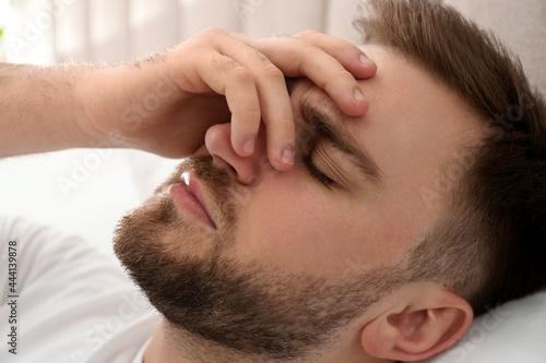 Fototapeta Naklejka Na Ścianę i Meble -  Young man suffering from migraine in bed, closeup