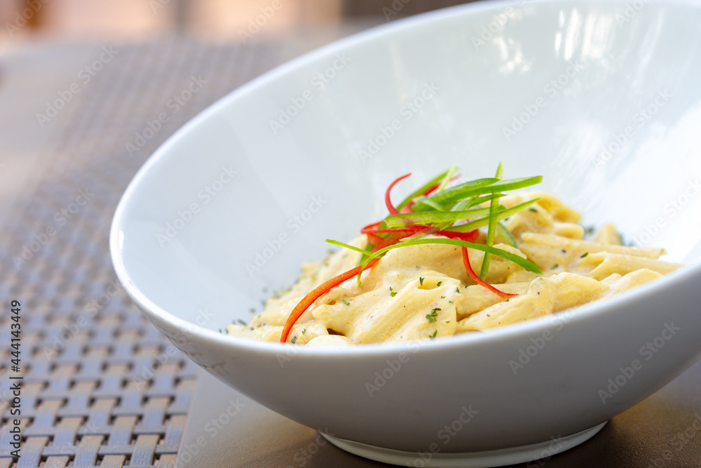 Side Shot of A Creamy Penne Pasta Alfredo With Julienned Bell Peppers On Top As Garnish. Side Shot of A Creamy Penne Pasta Alfredo With Julienned Bell Peppers On Top As Garnish.