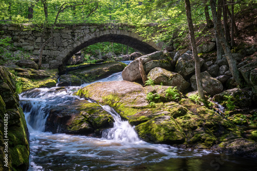 old stone arch bridge over waterfalls in the woods
