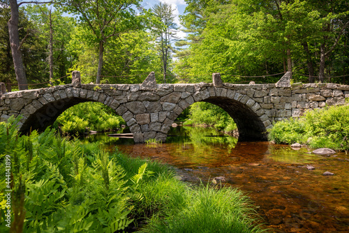 Old stone double arched bridge over calm waters in forest