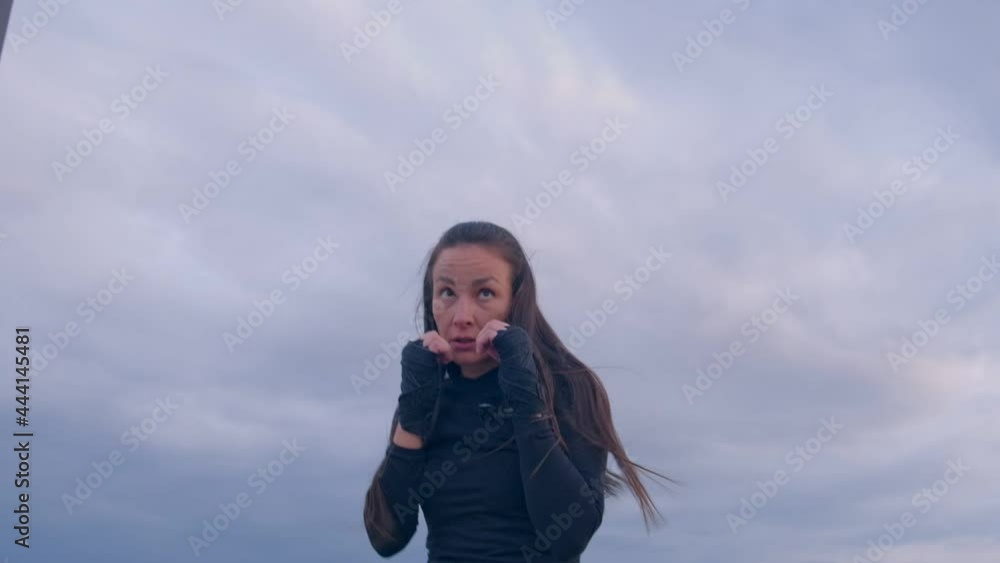 Beautiful young asian woman brunette fighter trains and hits a series of punches on the street. Shadow Fight Beautiful young asian woman brunette fighter trains and hits a series of punches on the street. Shadow Fight