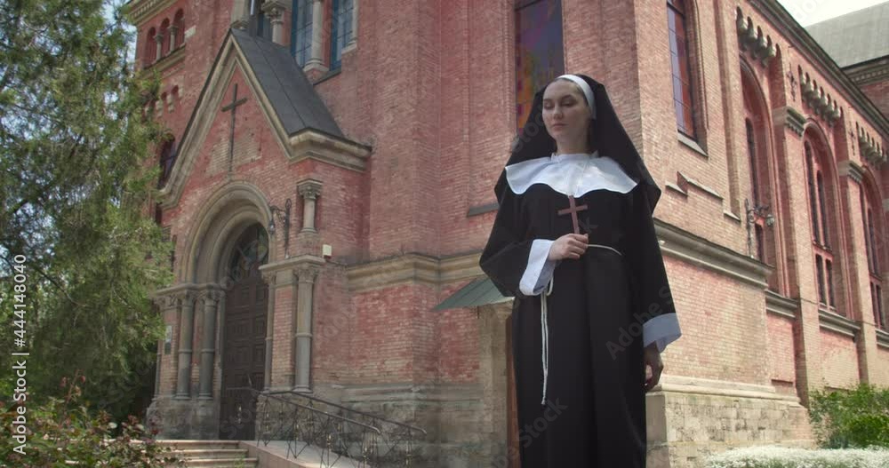 Young nun praying outdoors near monastery Young nun praying outdoors near monastery