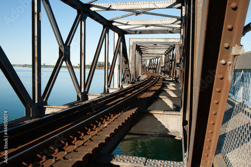 Rail lines lead and curve through the structure of steel truss bridge