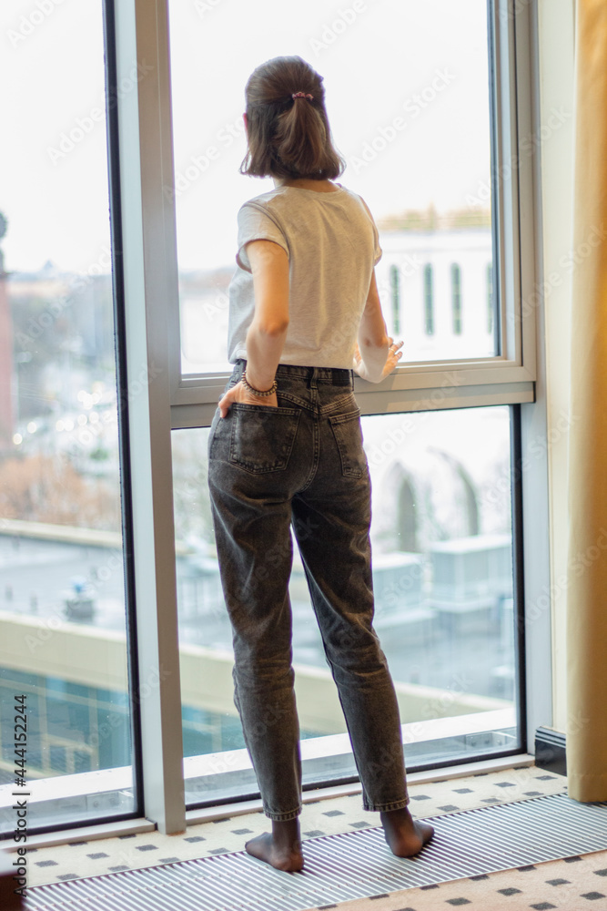 lonely girl standing by the window in the office back view lonely girl standing by the window in the office back view